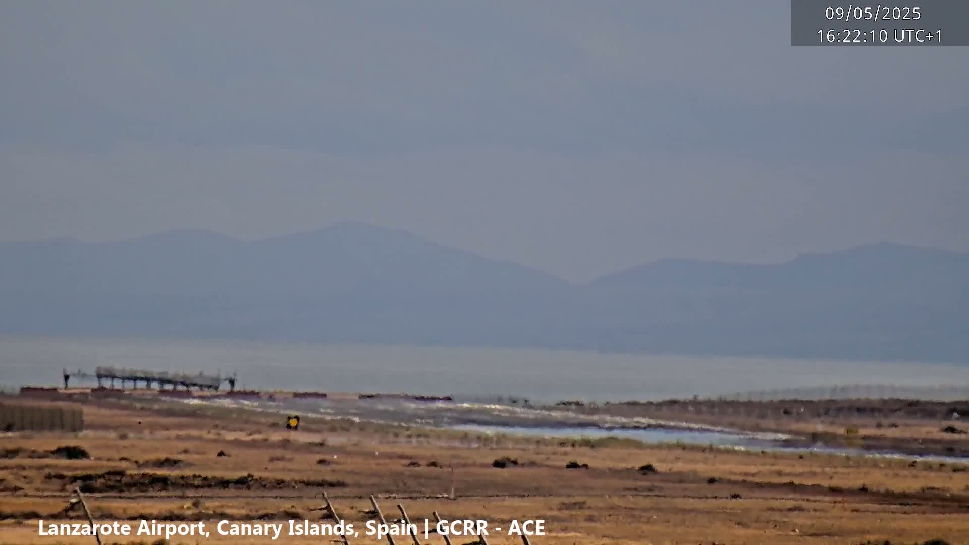 A hazy view of an airport with a distant mountain range under a muted sky.