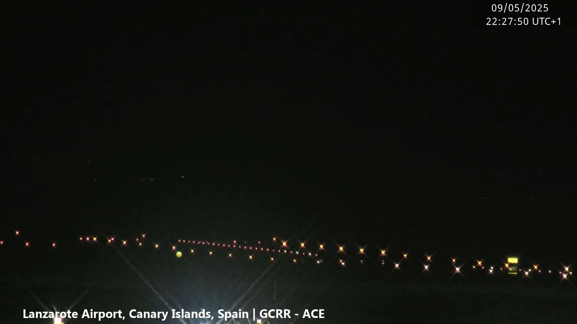 A nighttime, dark view of a runway illuminated by lights.