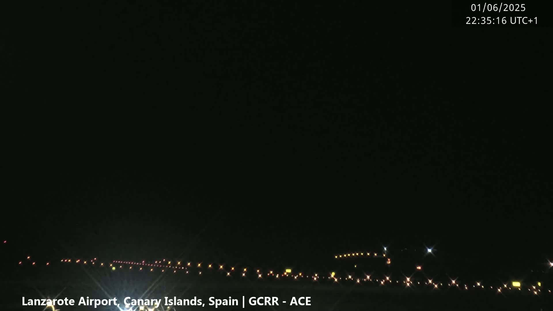 A nighttime view of an airport runway with its lights illuminated under a clear, dark sky.