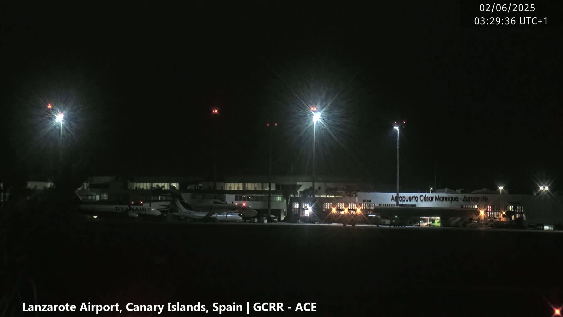 At night, several airplanes are parked at a brightly lit airport under a clear, dark sky.