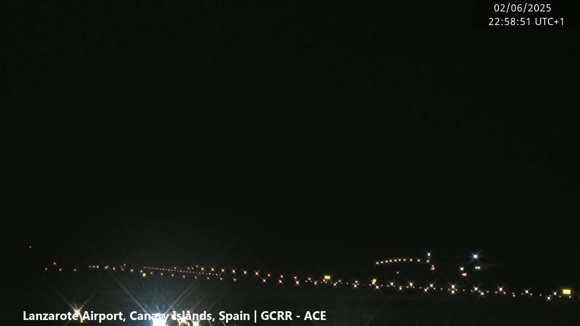 A nighttime long shot of a runway with lights illuminating the ground under a clear, dark sky.