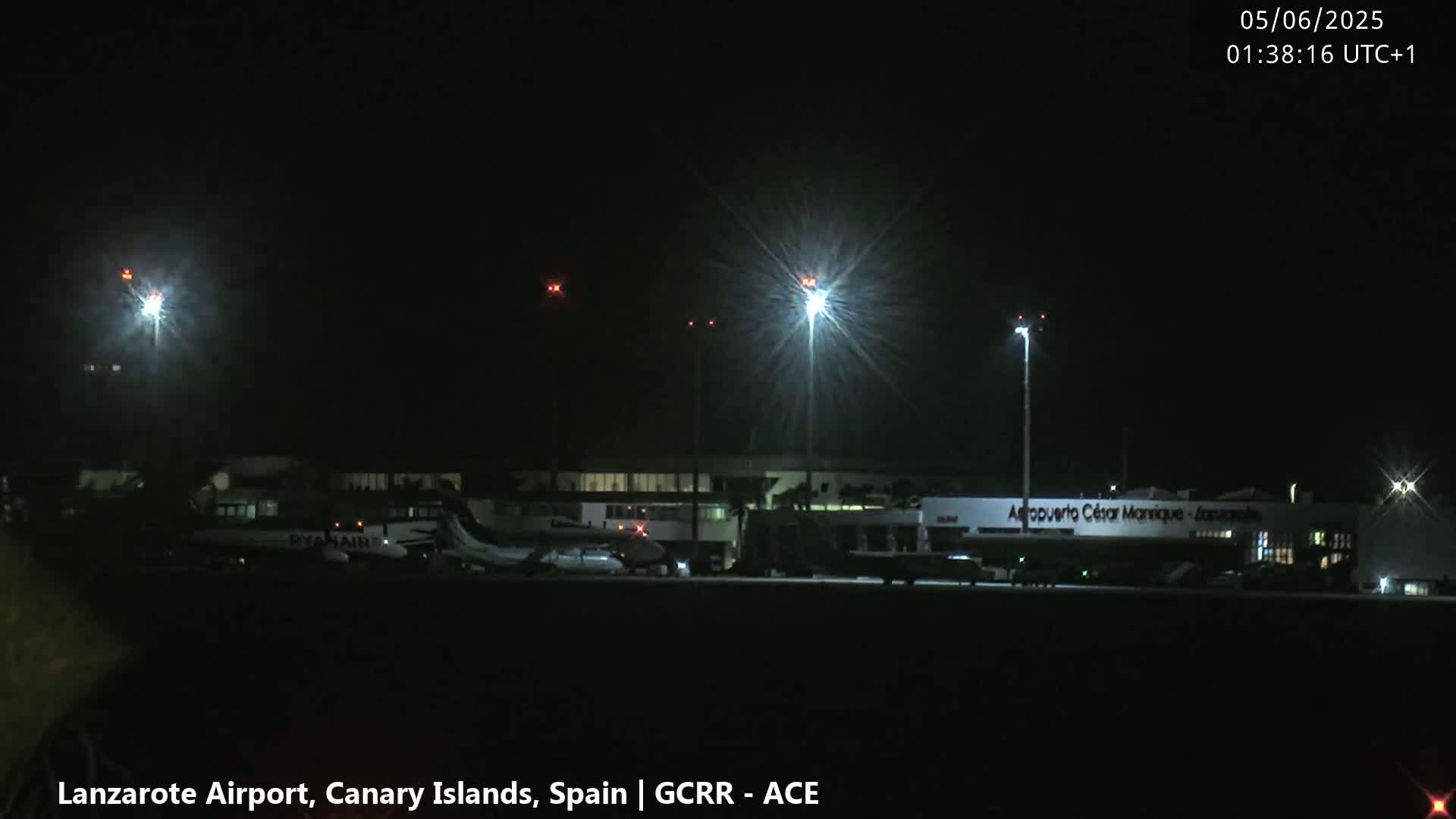 At night, several airplanes are parked at an airport under bright lights.