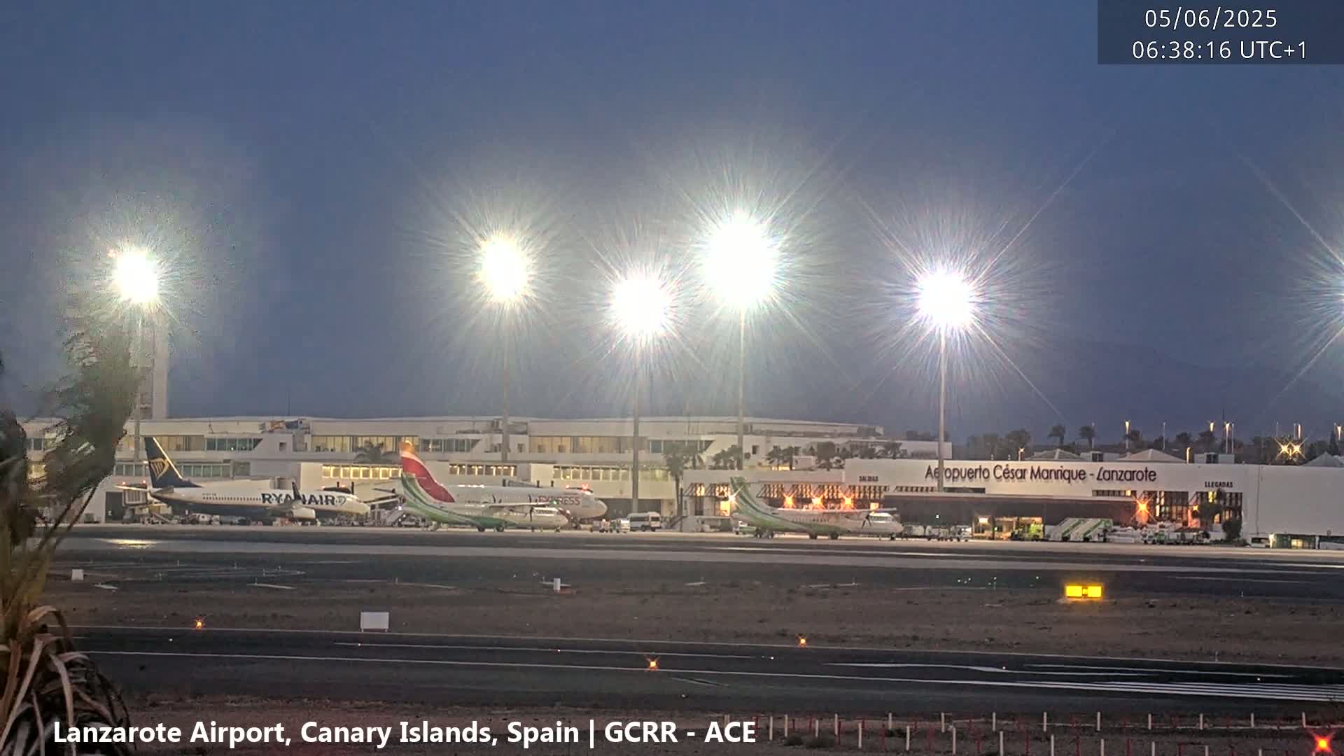 Several airplanes are parked at an airport under a twilight sky.