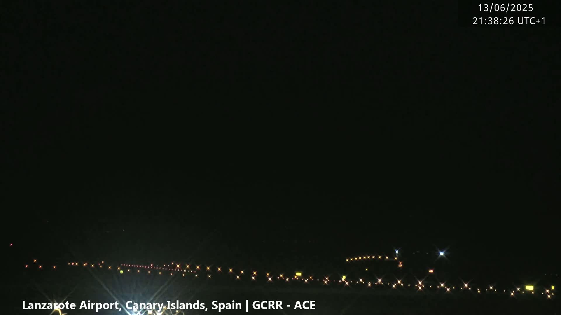 A nighttime view of an airport runway illuminated by lights under a clear, dark sky.