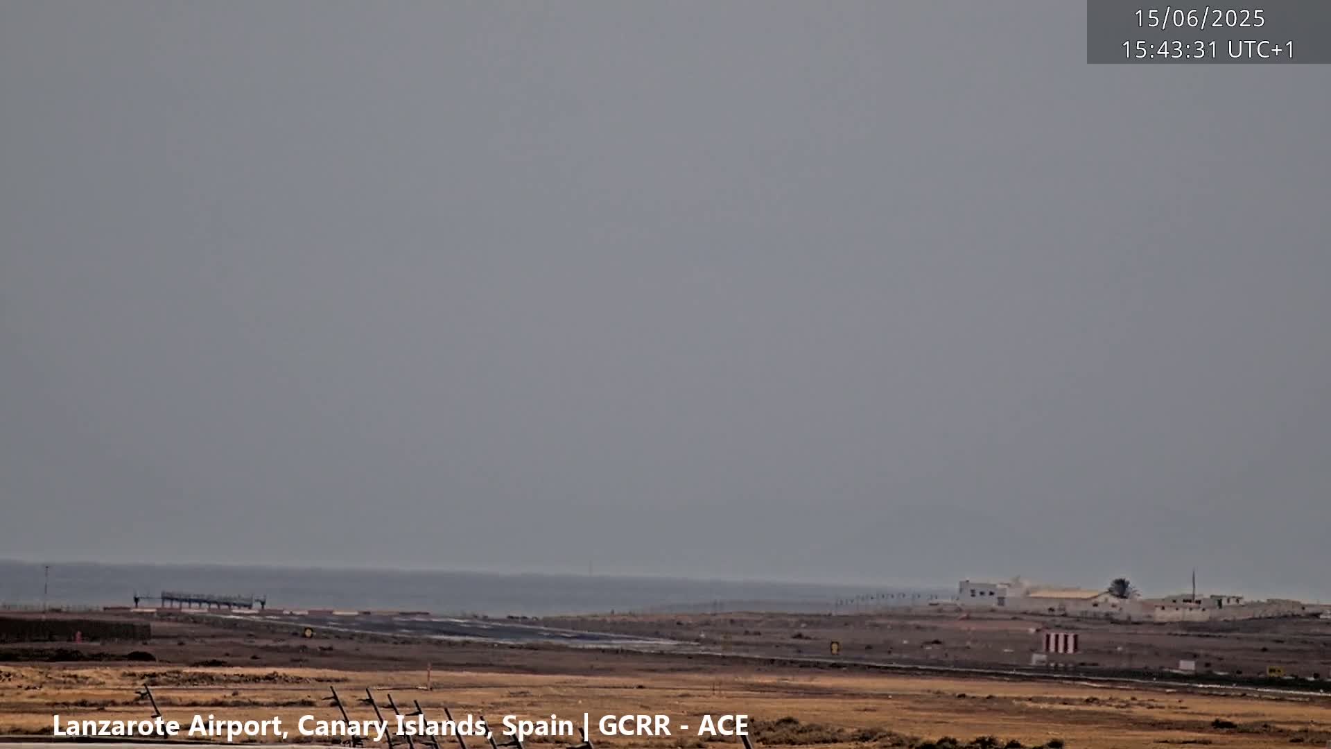 A hazy, overcast day reveals an airport runway and a distant ocean.