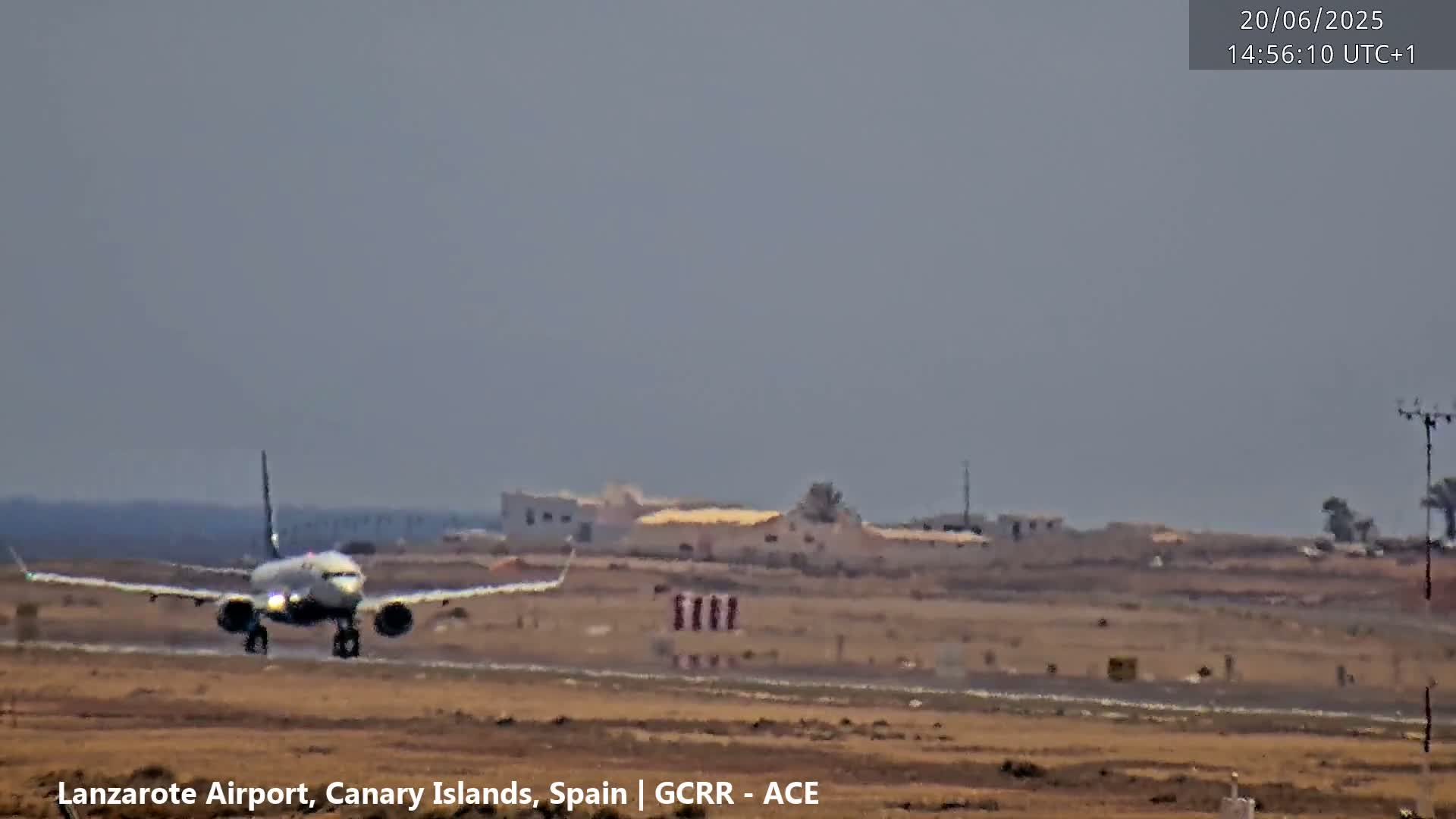 A passenger jet lands on a runway under hazy sky conditions.