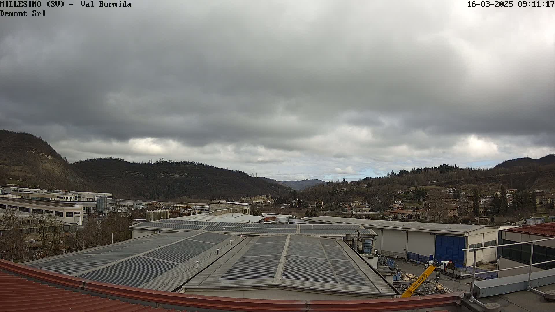 A view from a rooftop shows overcast skies over a valley of buildings and hills.