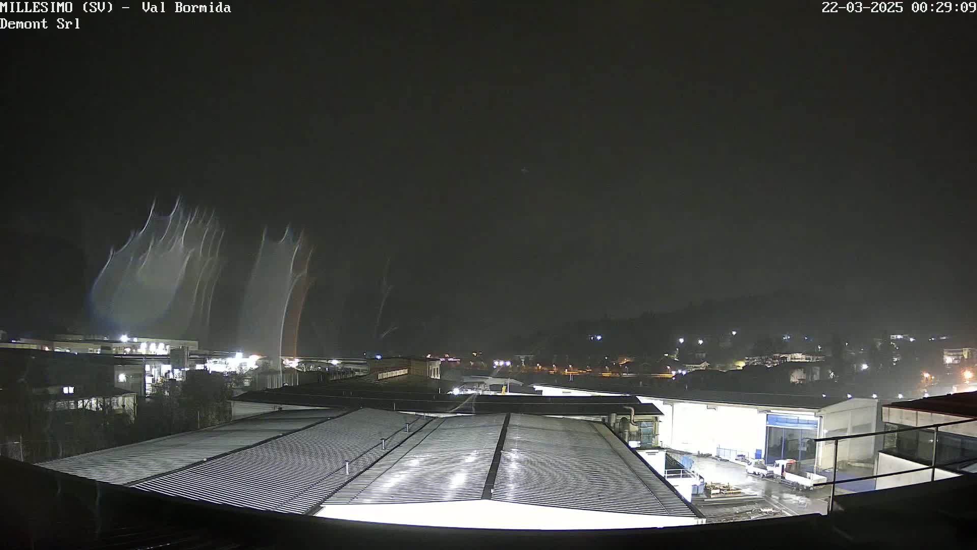 A nighttime view of an industrial area under a dark sky with streaks of light possibly from lightning or a similar phenomenon.