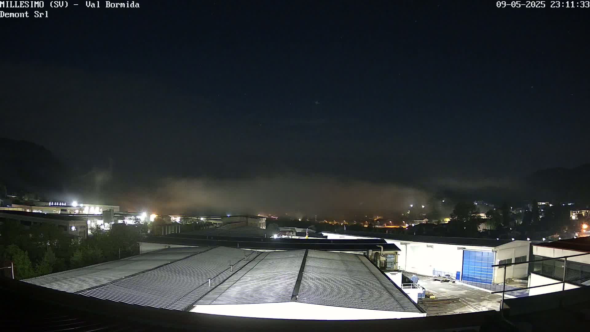 A nighttime view of an industrial area shrouded in low-lying fog under a dark, starry sky.