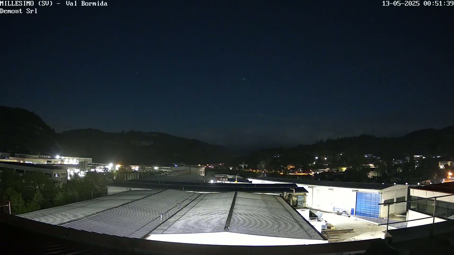 A nighttime view of an industrial area nestled in a valley, under a clear, starlit sky.