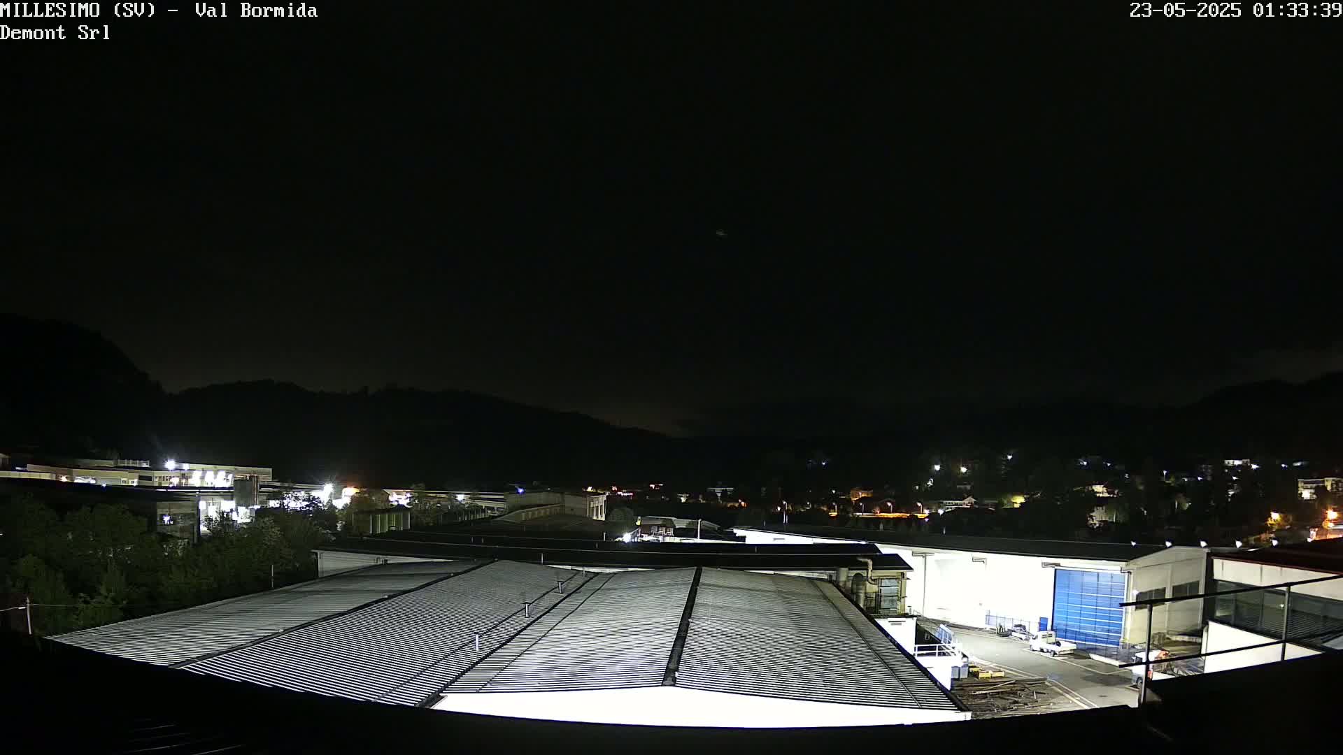 A nighttime view of an industrial area nestled in hills under a clear, dark sky.