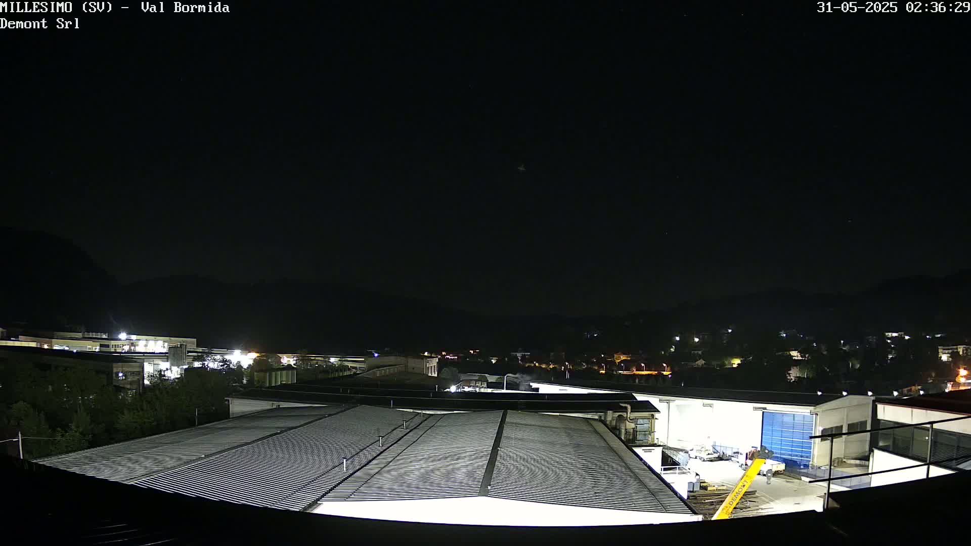 A nighttime view of an industrial area with several buildings, under a clear, dark sky.