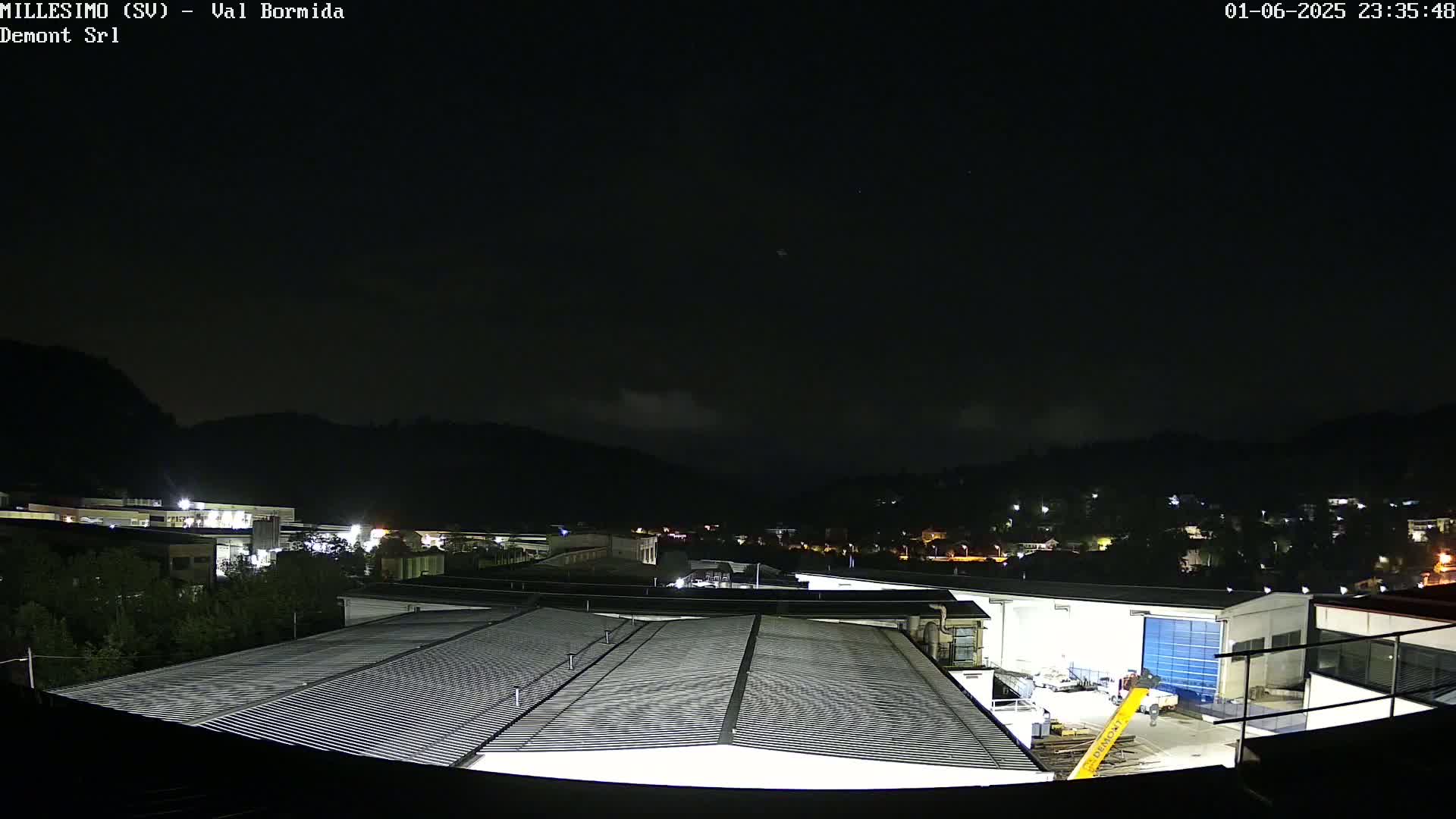 A nighttime view of an industrial area with factory buildings and a dark sky with a few clouds.
