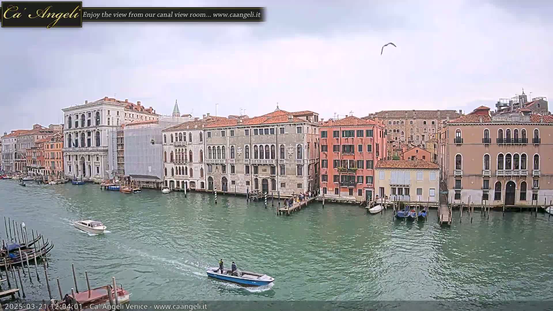 A canal in Venice, under an overcast sky, is lined with historic buildings and small boats.