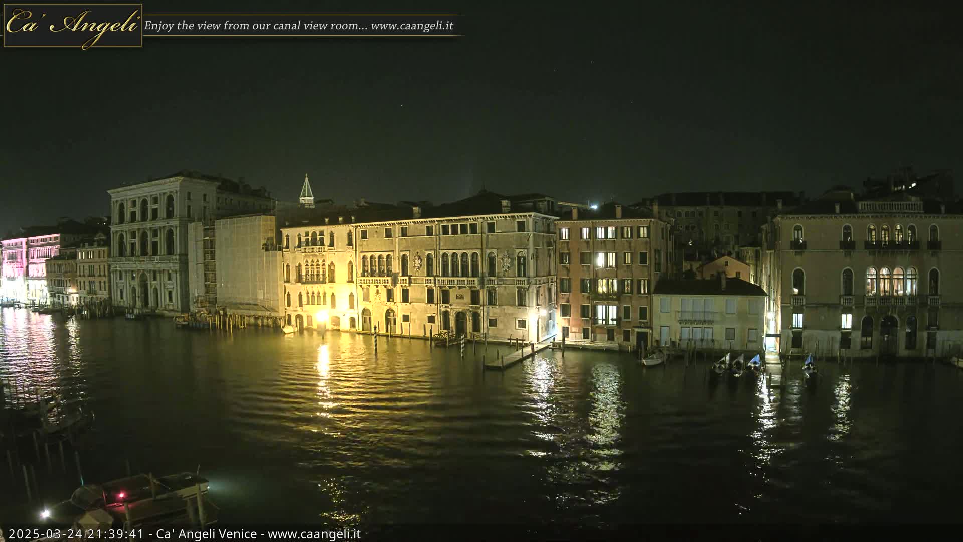 A nighttime view of several illuminated buildings lining a calm canal in Venice.