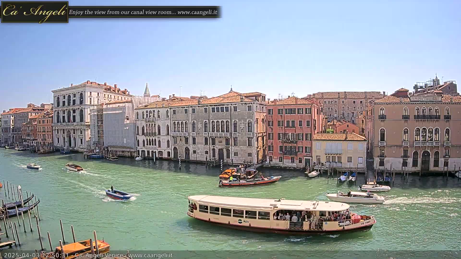 A sunny day in Venice shows numerous boats on a canal lined with historic buildings.