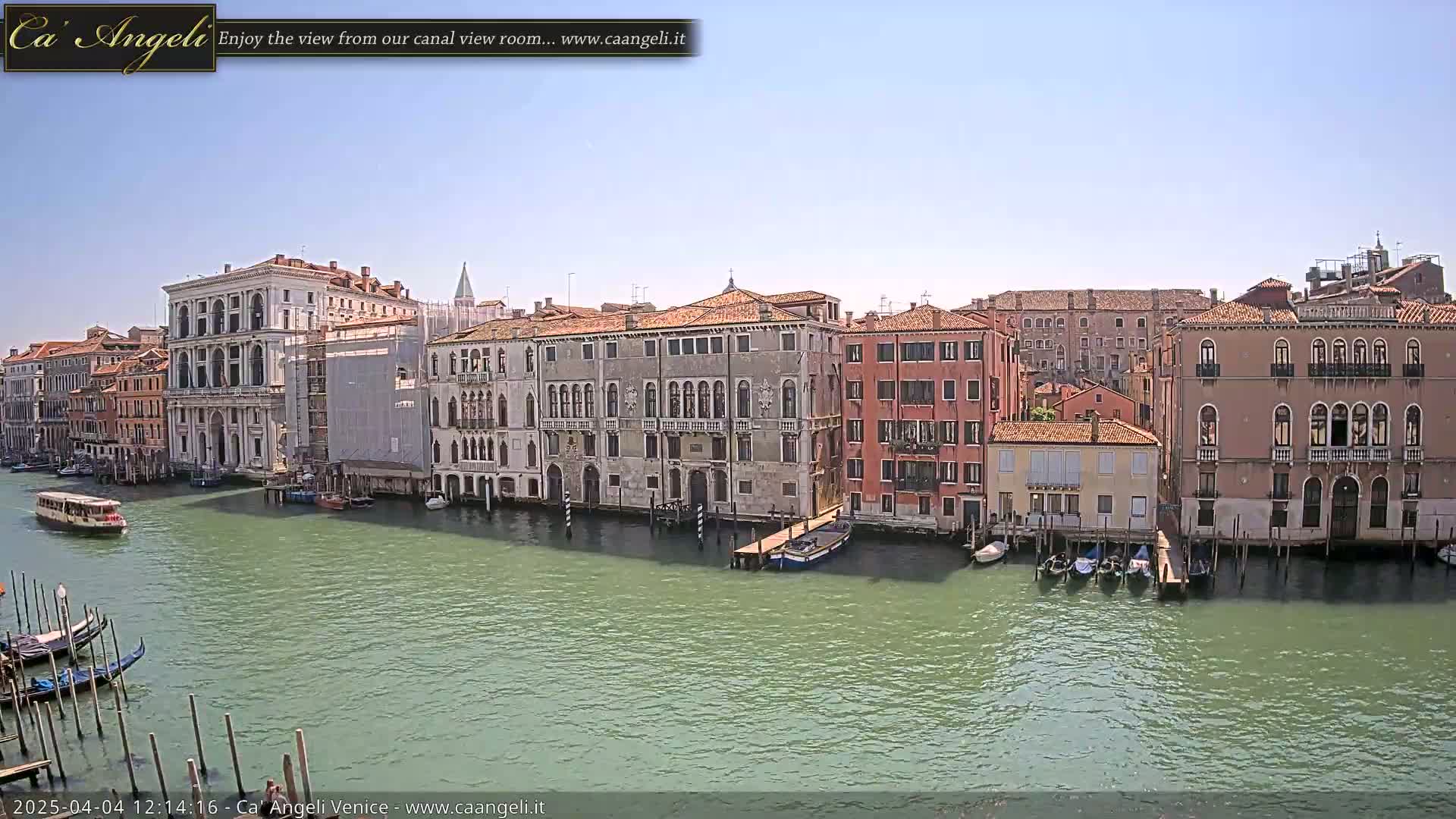A sunny day in Venice shows a canal lined with historic buildings, gondolas, and a water bus.