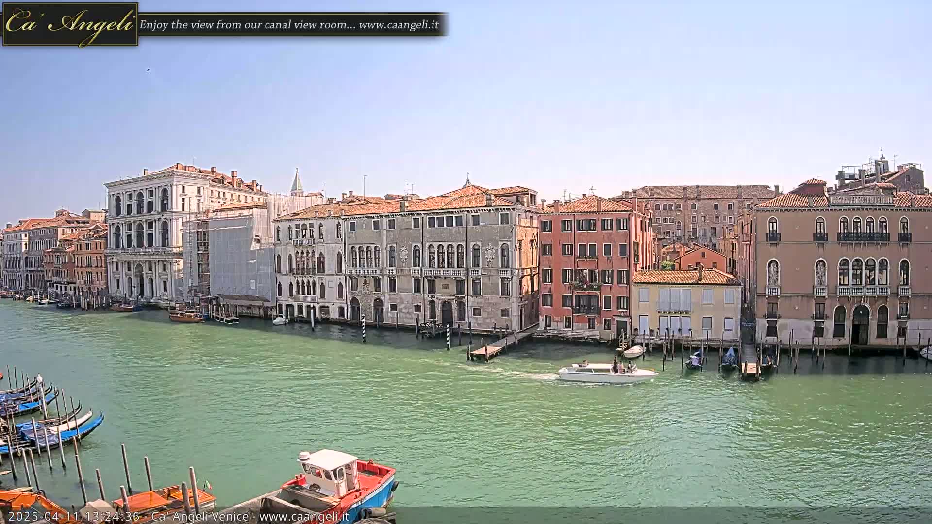 A sunny day in Venice shows a canal lined with historic buildings, boats, and gondolas.