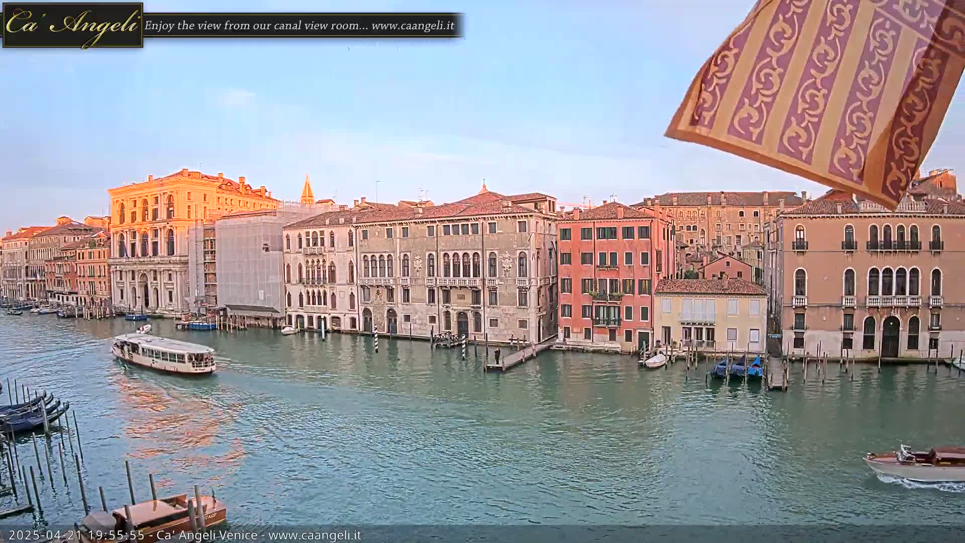 A calm canal in Venice, Italy, at sunset, is lined with historic buildings and boats.