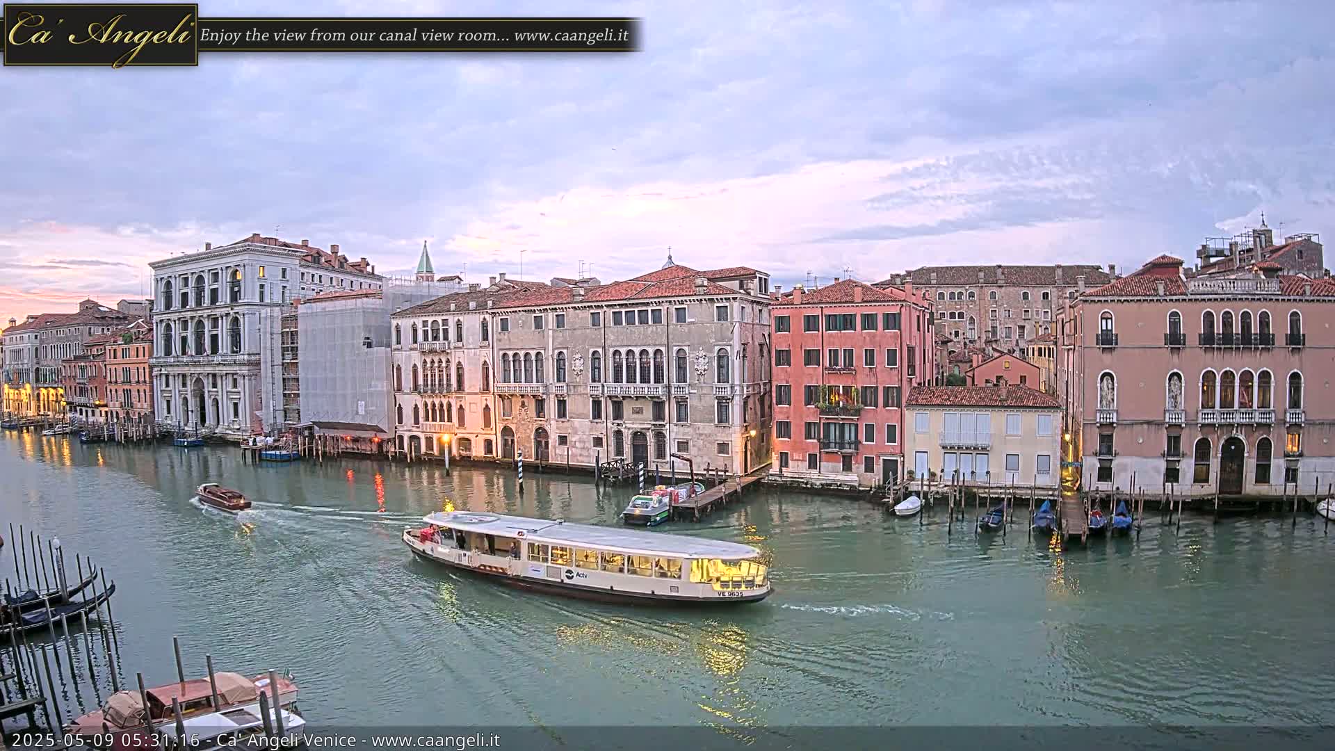 A waterway with several boats is lined with historic buildings under a cloudy sky.