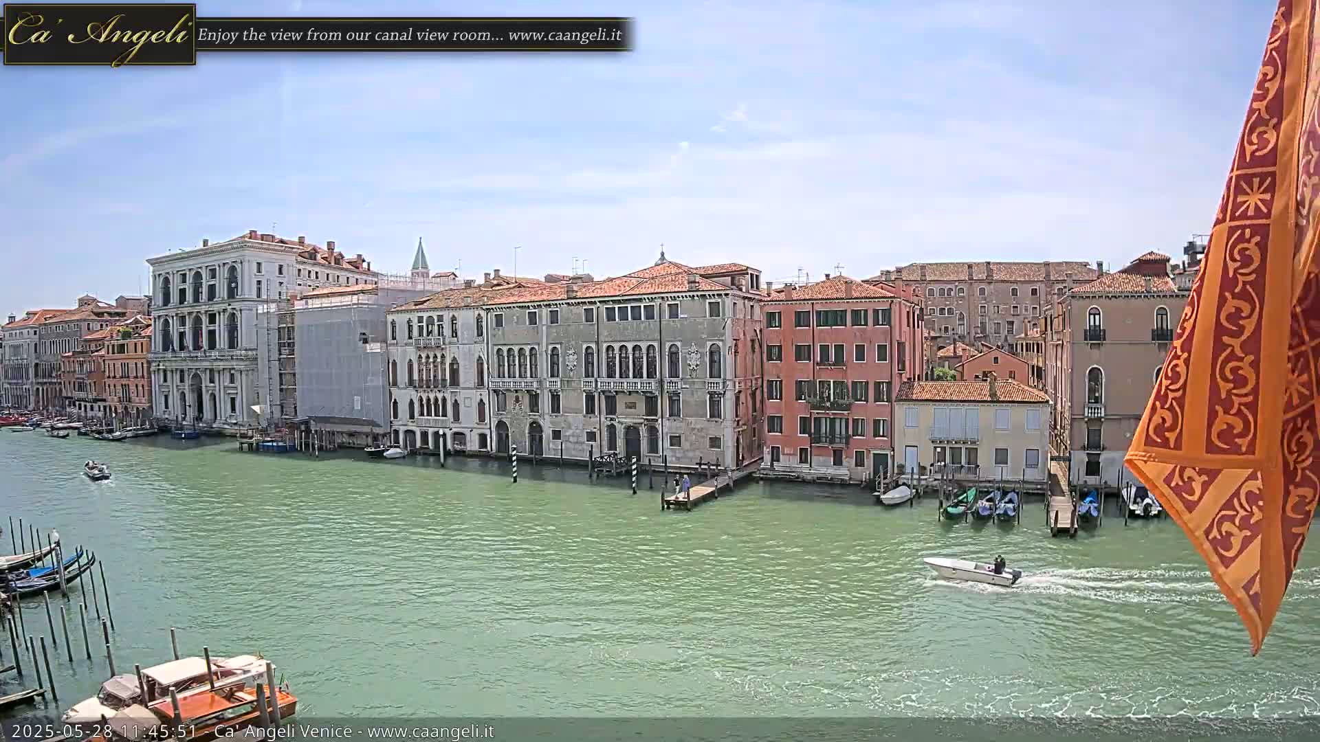 A canal in Venice, Italy, on a sunny day, is lined with historic buildings and boats.