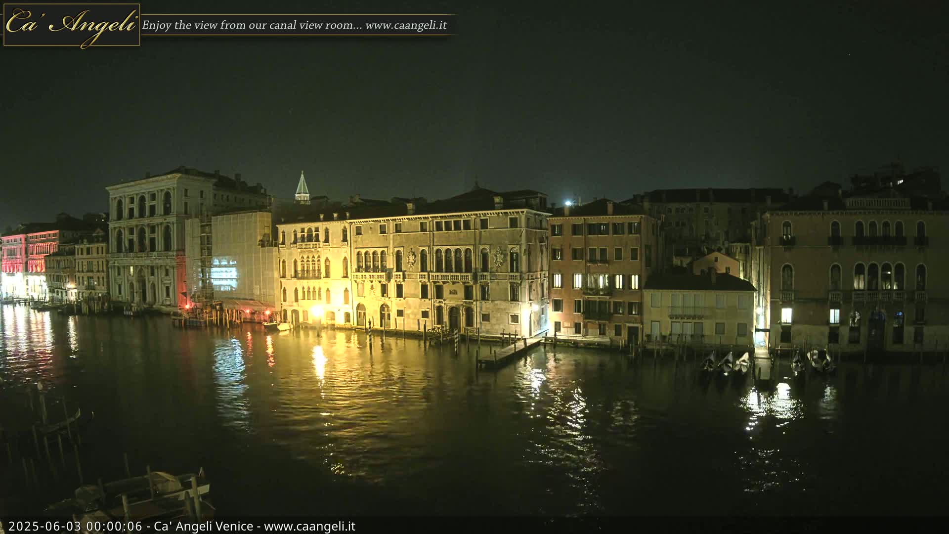 At night, illuminated buildings line a calm canal reflecting their lights on the dark water.