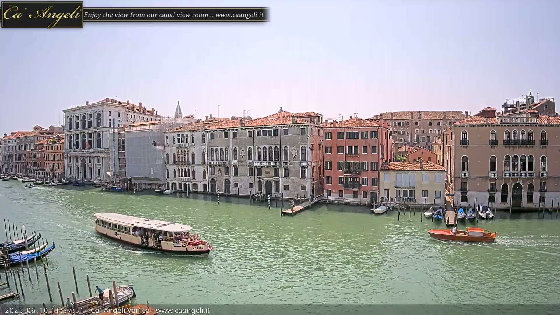 A waterway with several Venetian buildings along its banks on a sunny day, showing a water bus and other boats on the water.
