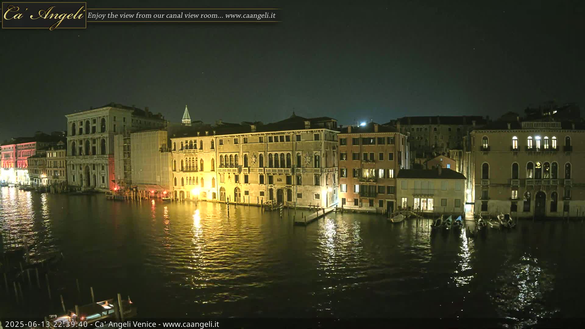 A nighttime view of illuminated buildings along a calm canal in Venice.