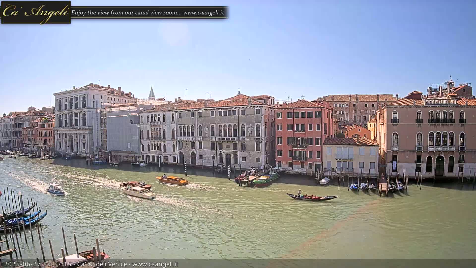 A sunny day in Venice shows several boats on a canal lined with historic buildings.