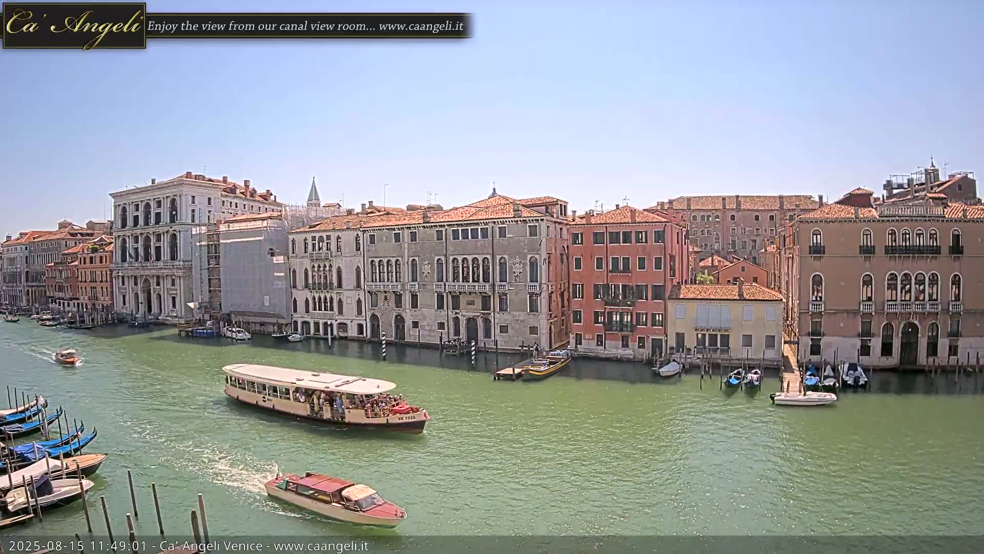 A canal in Venice, under an overcast sky, is lined with historic buildings, with several boats and gondolas on the water.