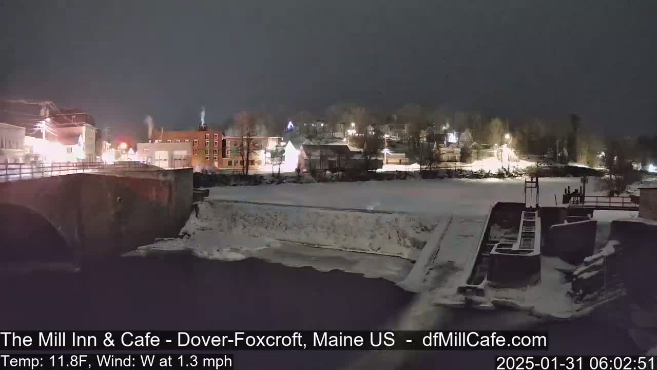 A snow-covered river flows past a town at night, illuminated by streetlights.