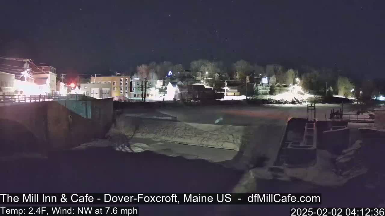 A nighttime view of a snow-covered town beside a partially frozen river, under a clear, starry sky with a northwest wind.