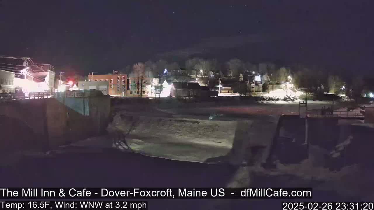 A nighttime view of a snow-covered river flowing past a town under a clear, starry sky.