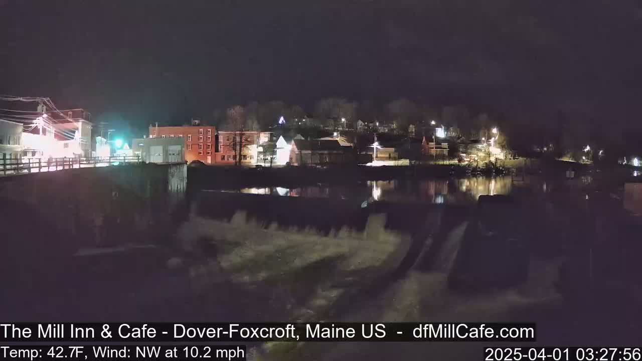 A nighttime view of a town across a calm body of water, with a cool temperature and a northwest wind.