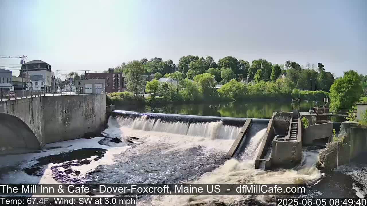 Water flows over a dam in a town on a partly sunny day with a southwest wind of 3 mph and a temperature of 67.4°F.