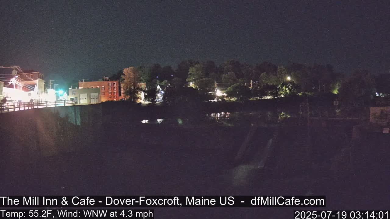 A nighttime view of a town by a river, under a clear, dark sky.