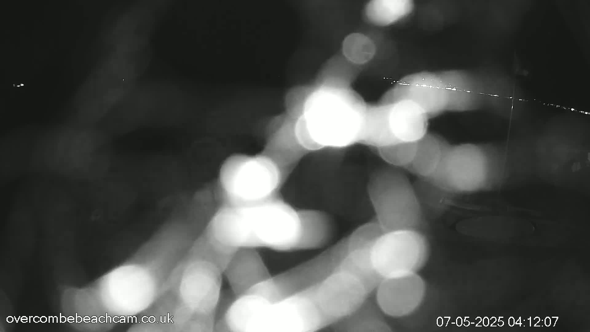 Blurred, out-of-focus nighttime lights are visible through a rain-streaked surface.