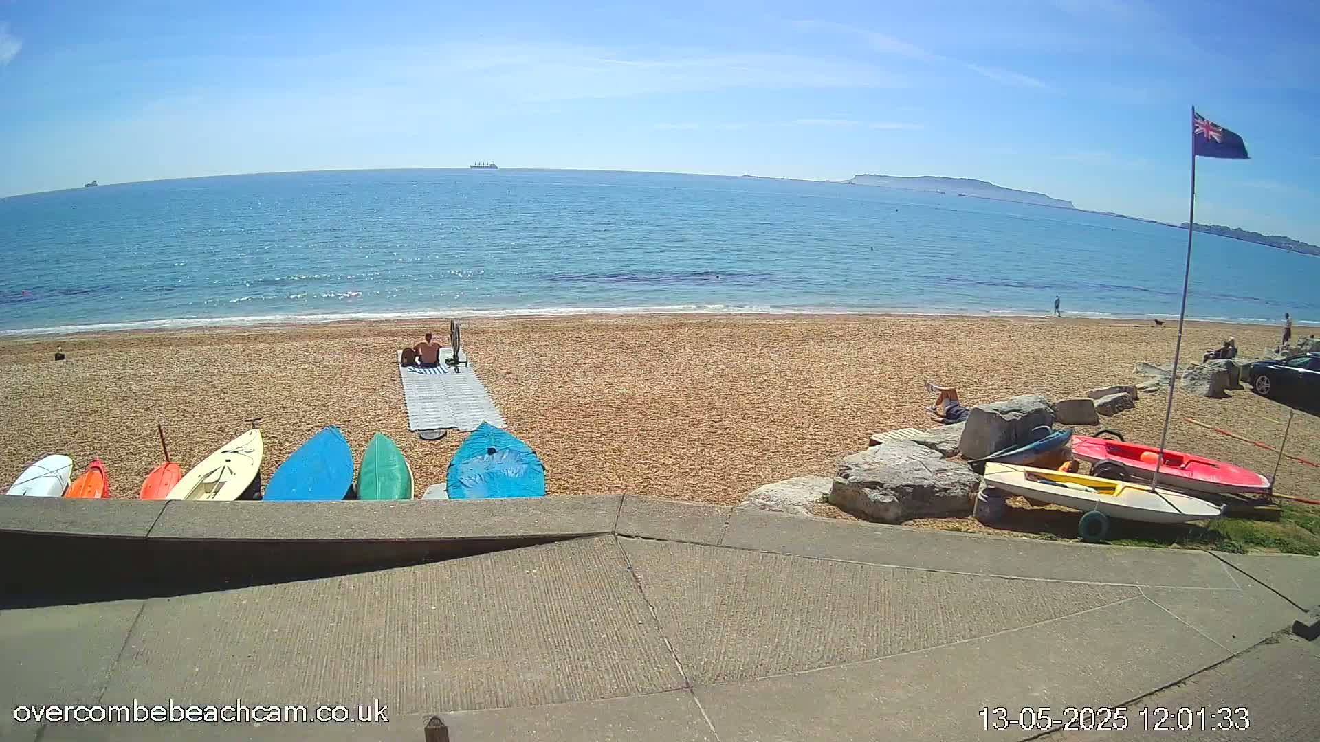 A sandy beach with several small boats and a few people on a sunny day.