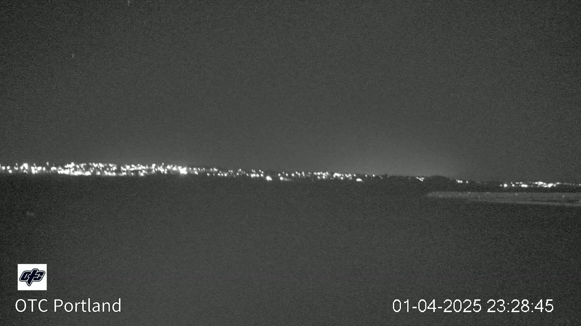 A nighttime long shot shows a distant line of city lights under a dark sky.