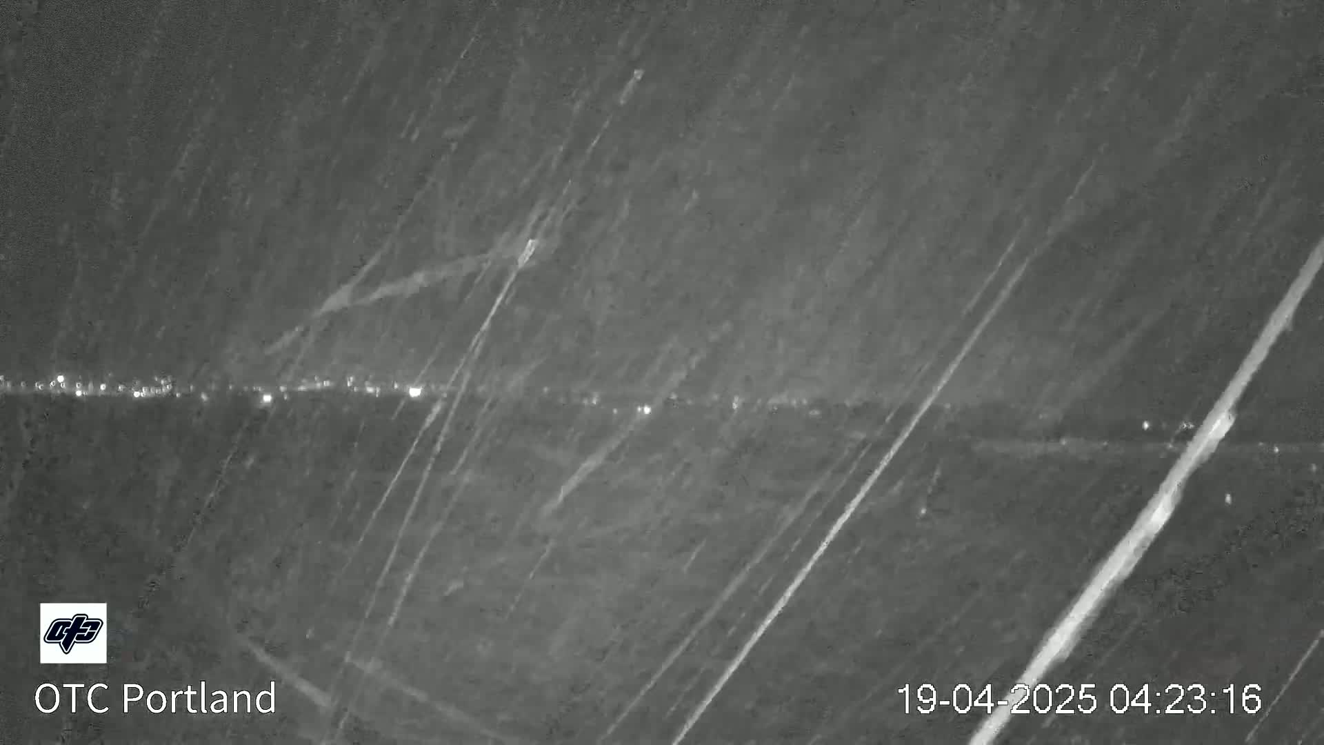 A nighttime view of a distant line of lights under heavy rain or snow.