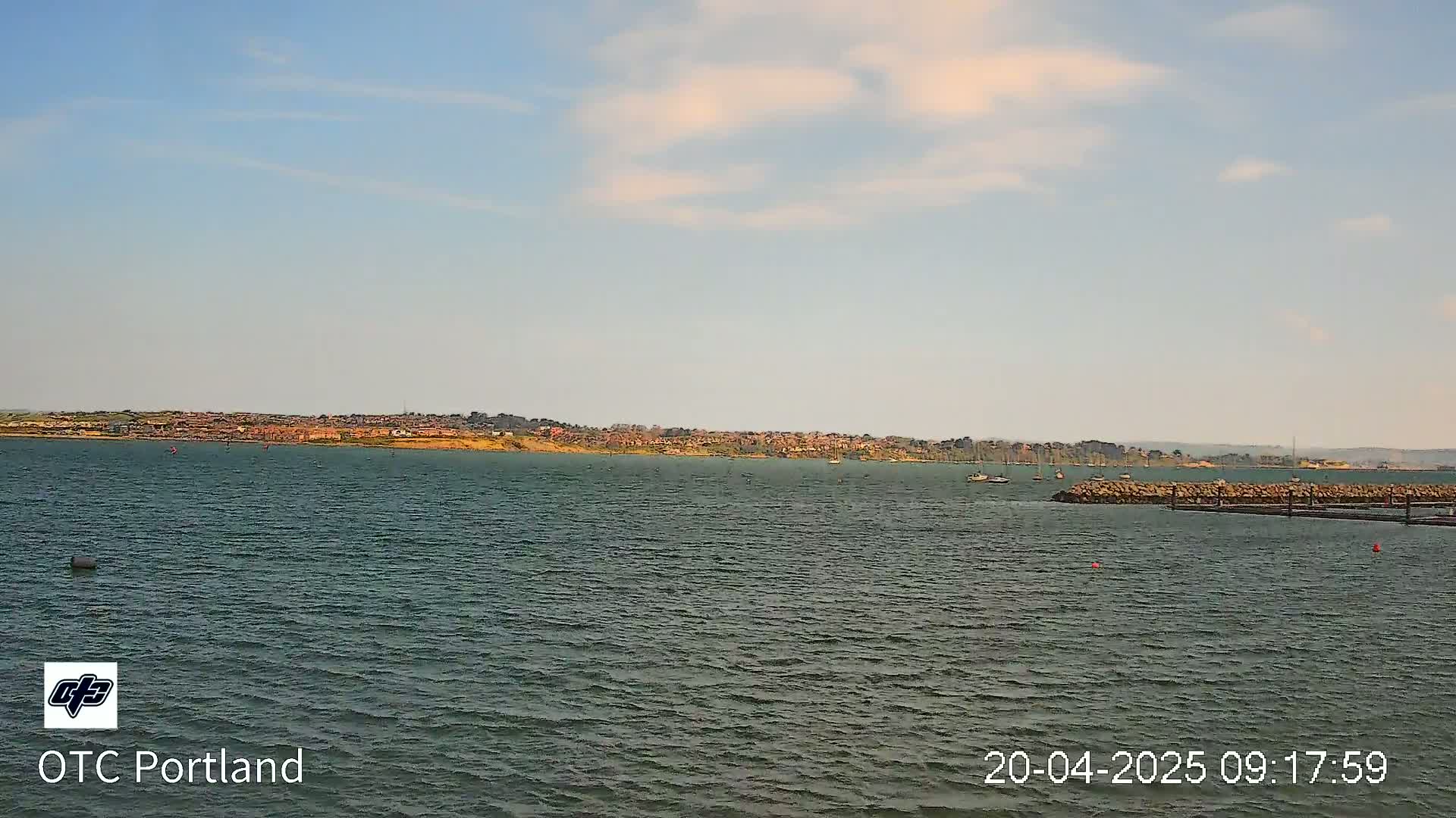 A body of water shows a distant shoreline with buildings under a mostly clear sky.