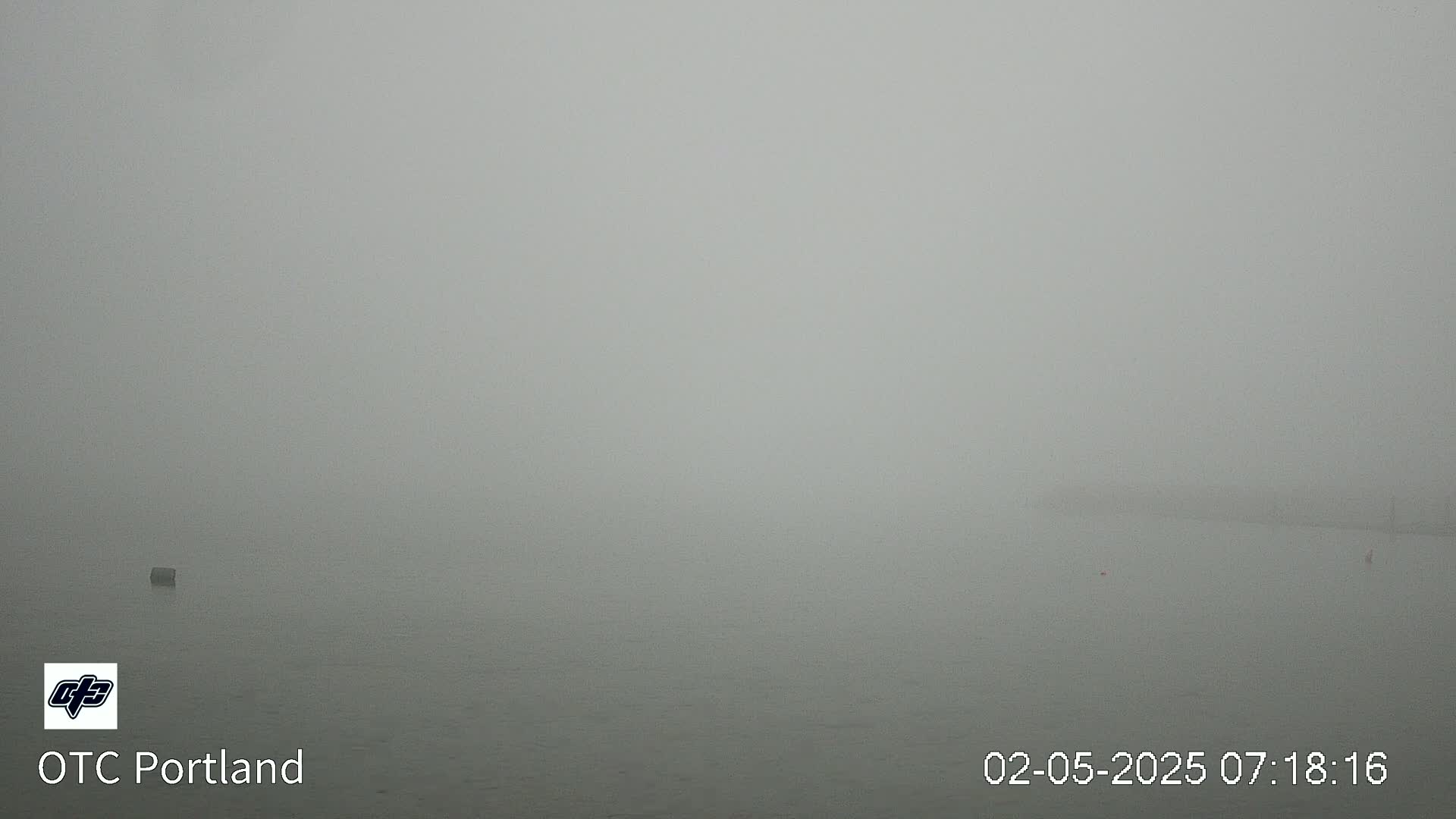 A very foggy body of water is visible, with a few indistinct objects barely perceptible in the distance.