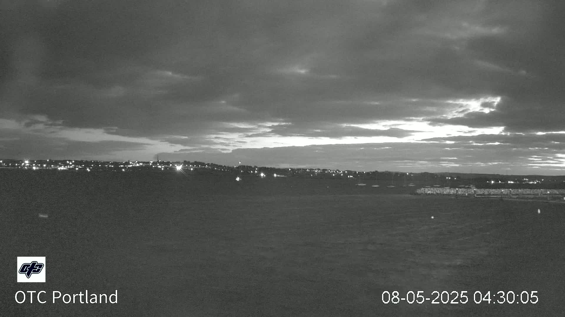 A nighttime view of a city skyline under a cloudy, dusky sky.