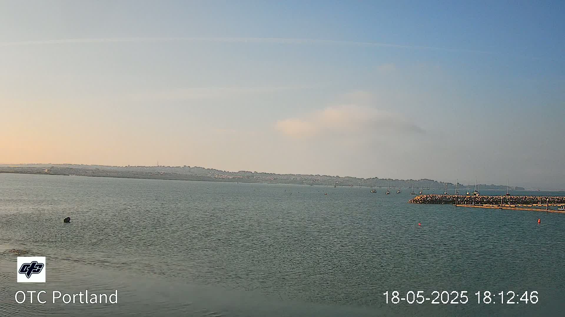 A calm body of water with a distant shoreline under a partly cloudy sky.
