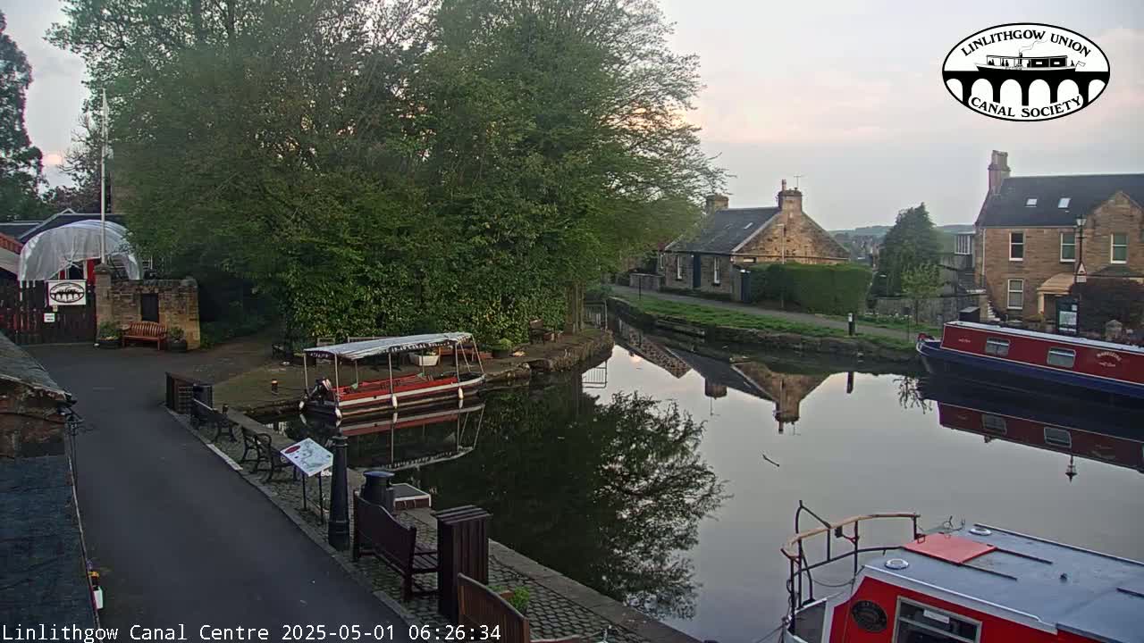 A calm canal reflects buildings and boats under a twilight sky.