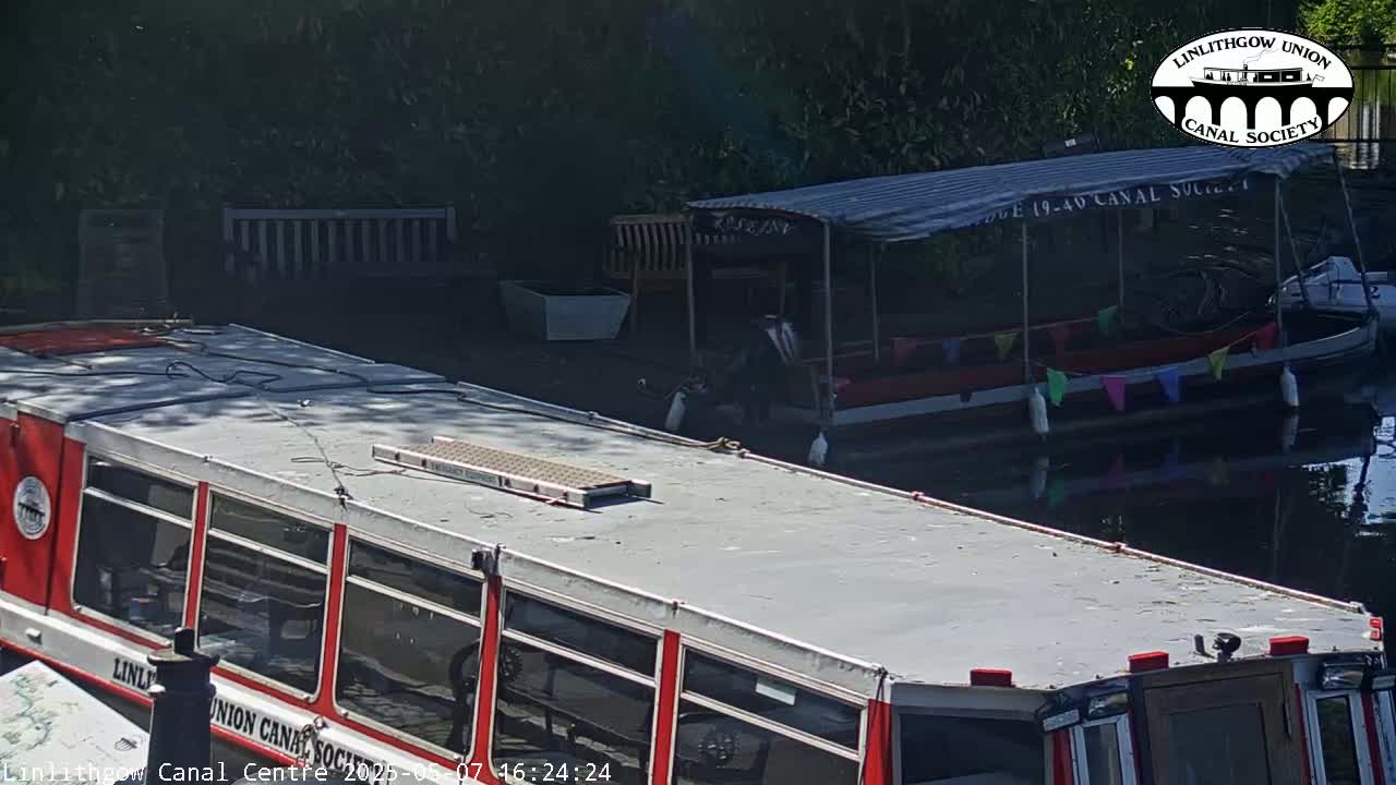 Two canal boats are moored next to each other on a sunny day.