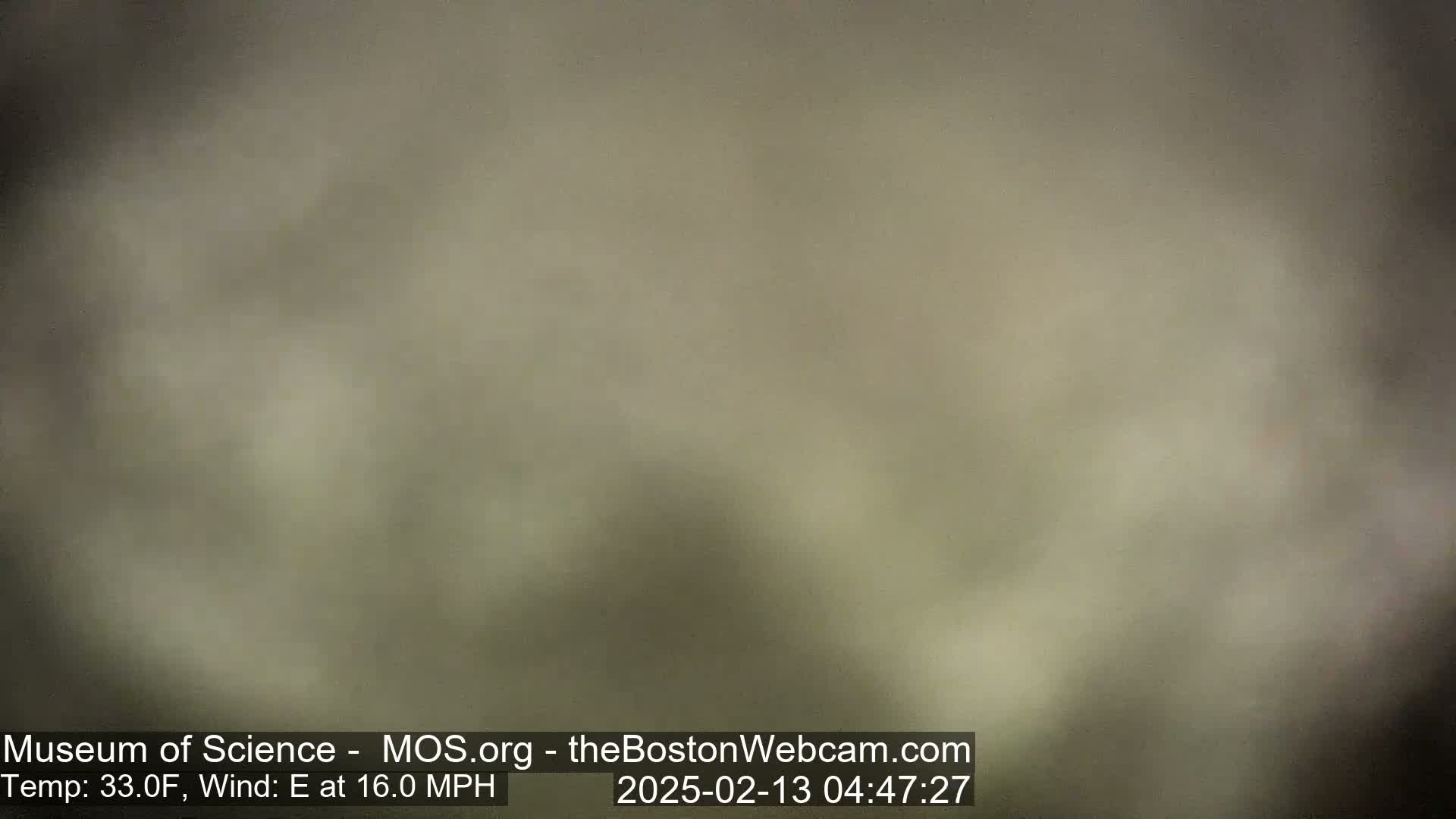 A blurry, muted-brown image shows an overcast sky with an east wind of 16 mph and a temperature of 33°F.