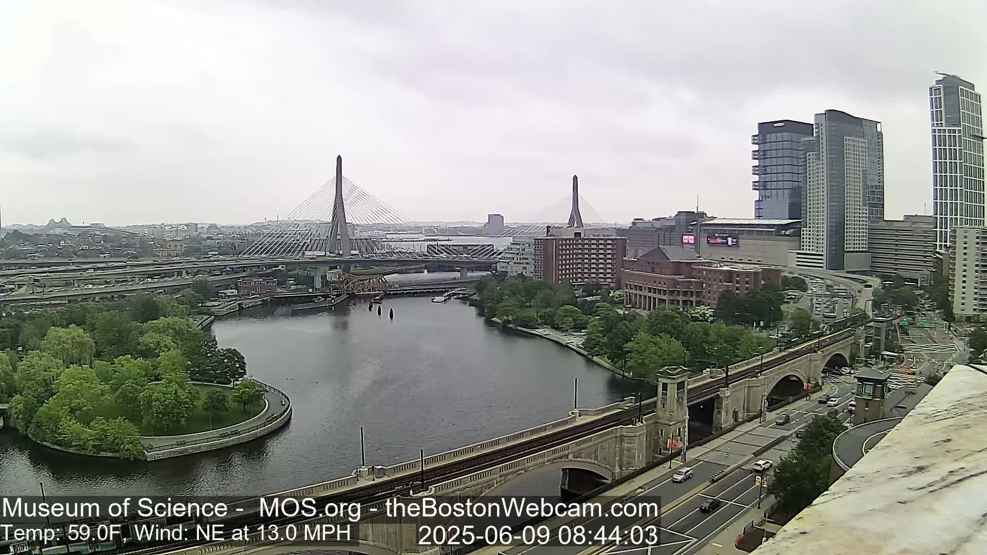 A long shot of a city with a river, bridges, and high-rise buildings under an overcast sky.