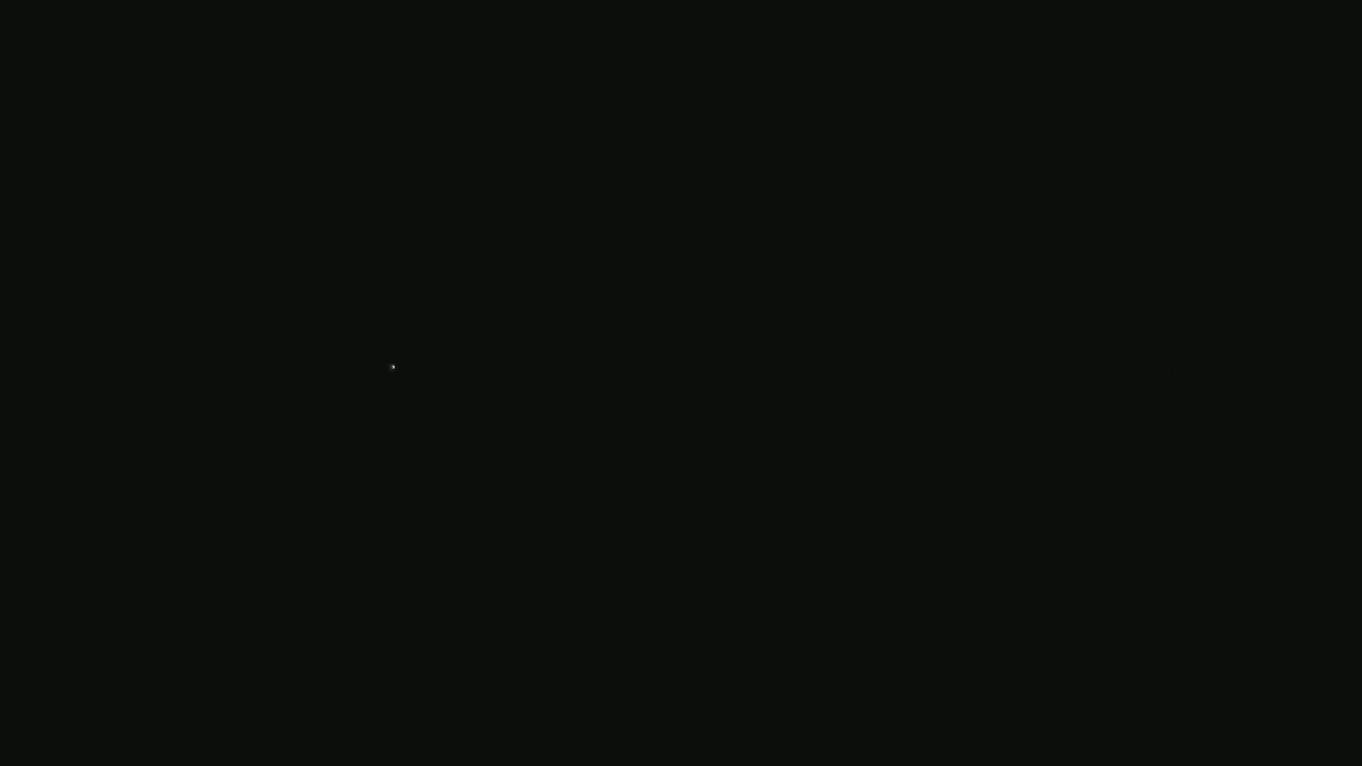The image shows a nearly completely black screen with a single, faint white speck near the center.