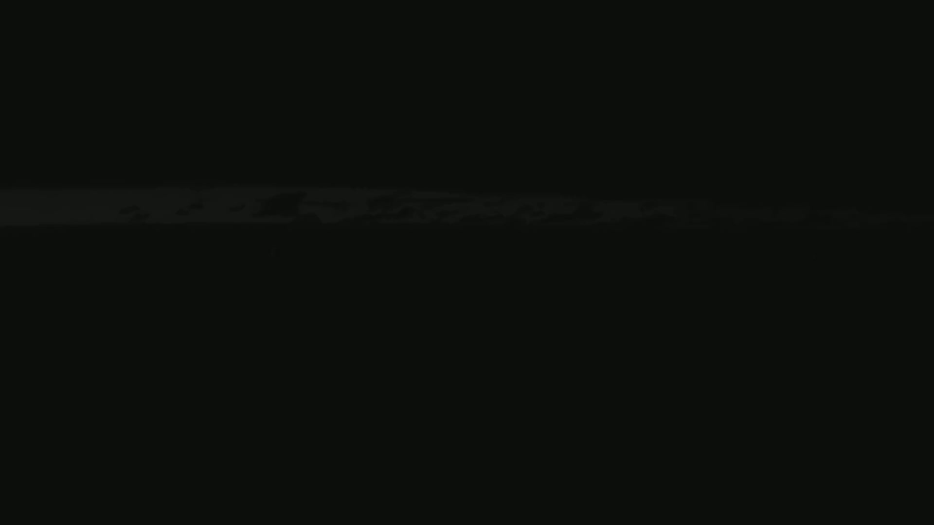 A low-light, dark image shows a thin horizontal band of lighter gray across the bottom, possibly clouds at night or a very dimly lit landscape.